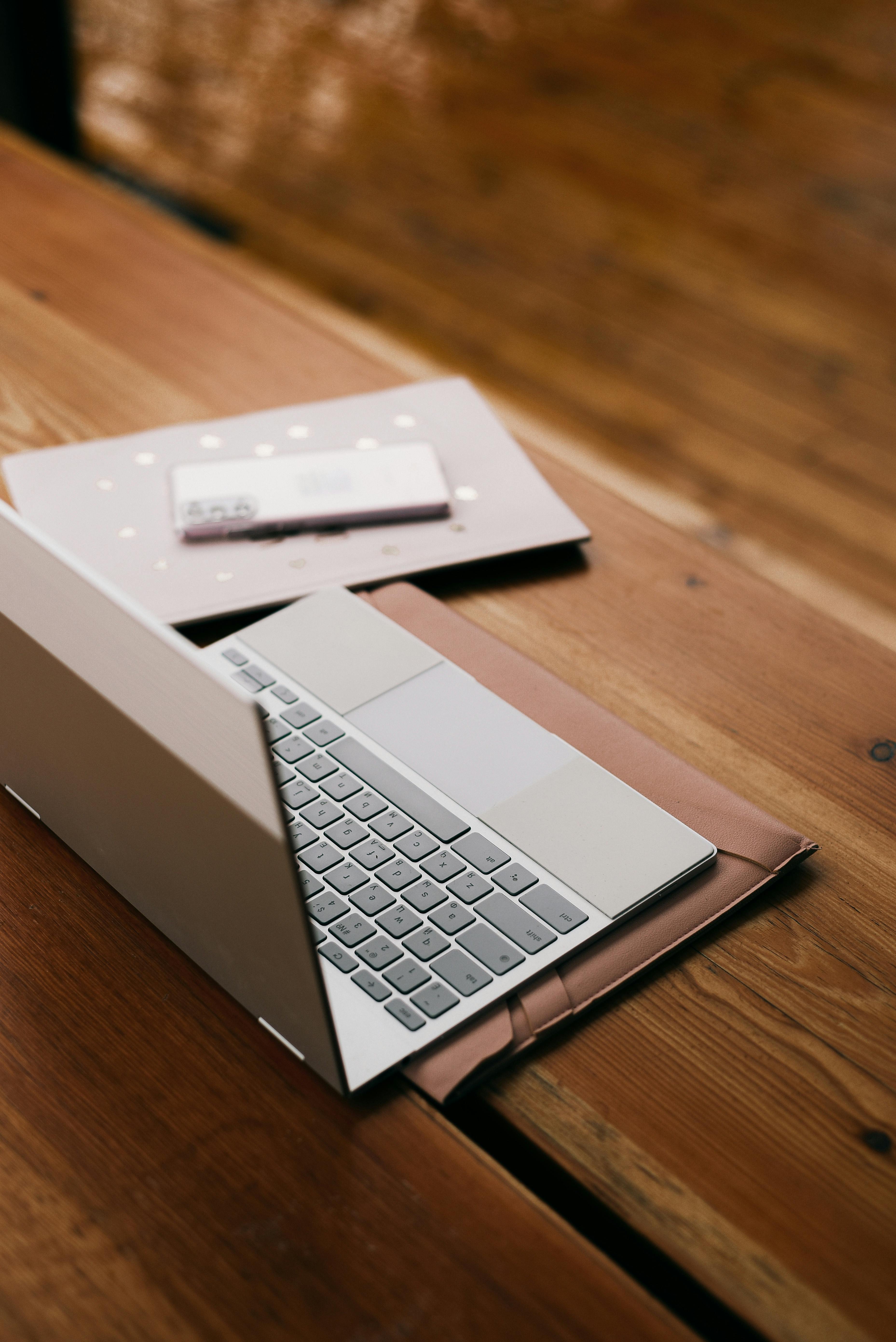 Open laptop and notebook with stylus on a warm wood desk